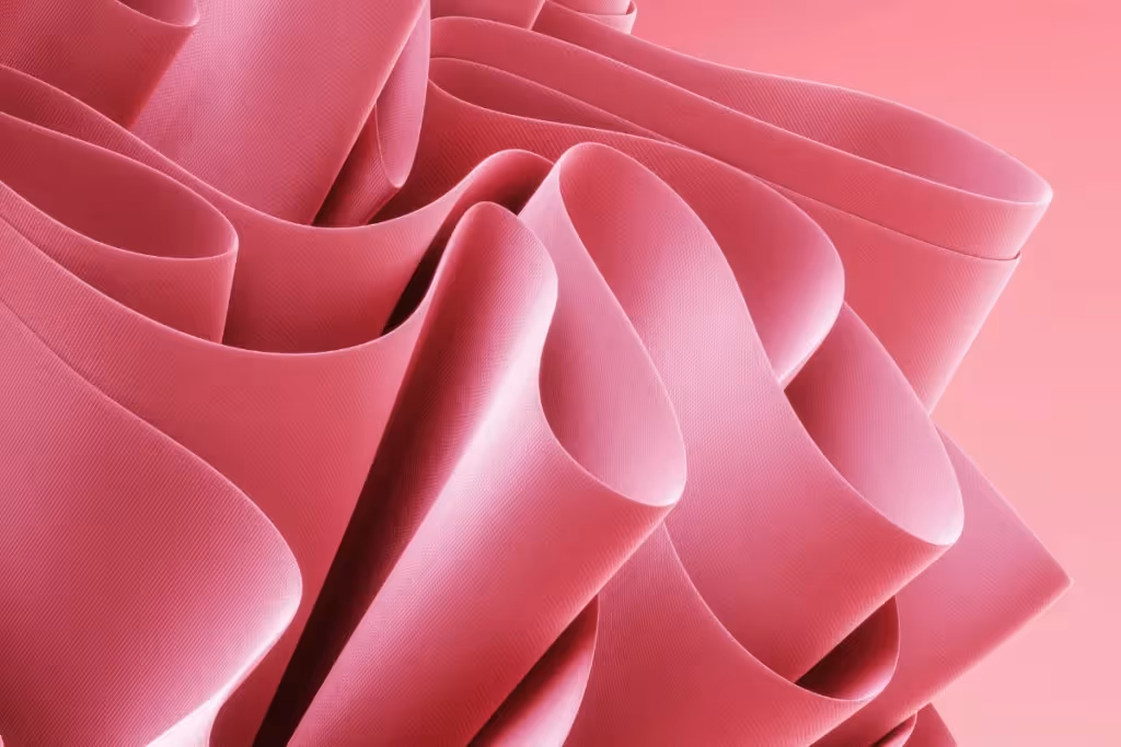 Soft and elegant pink fabric flowing in smooth, undulating waves, creating a delicate texture.