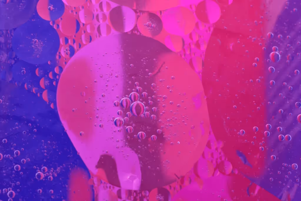 A colorful abstract image featuring large and small bubbles floating in a purple and pink gradient background.