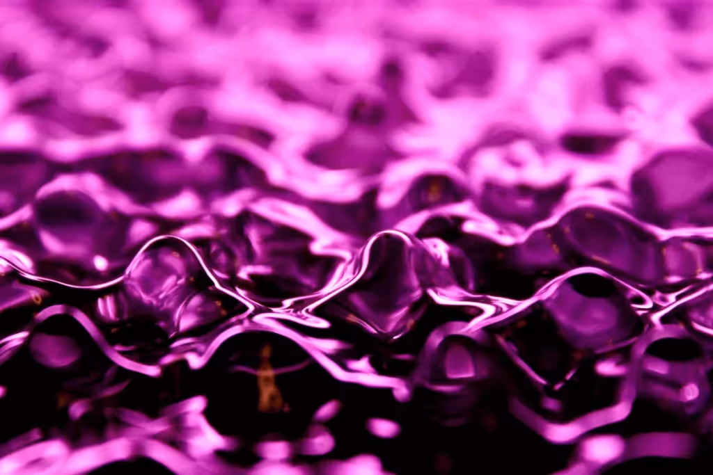 Abstract close-up of fluid purple waves, with shimmering reflections creating a smooth, rippling surface effect.