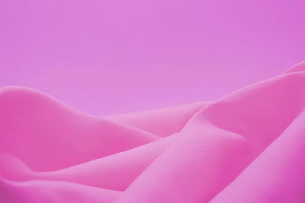 Close-up of soft pink fabric folds against a smooth gradient pink background.