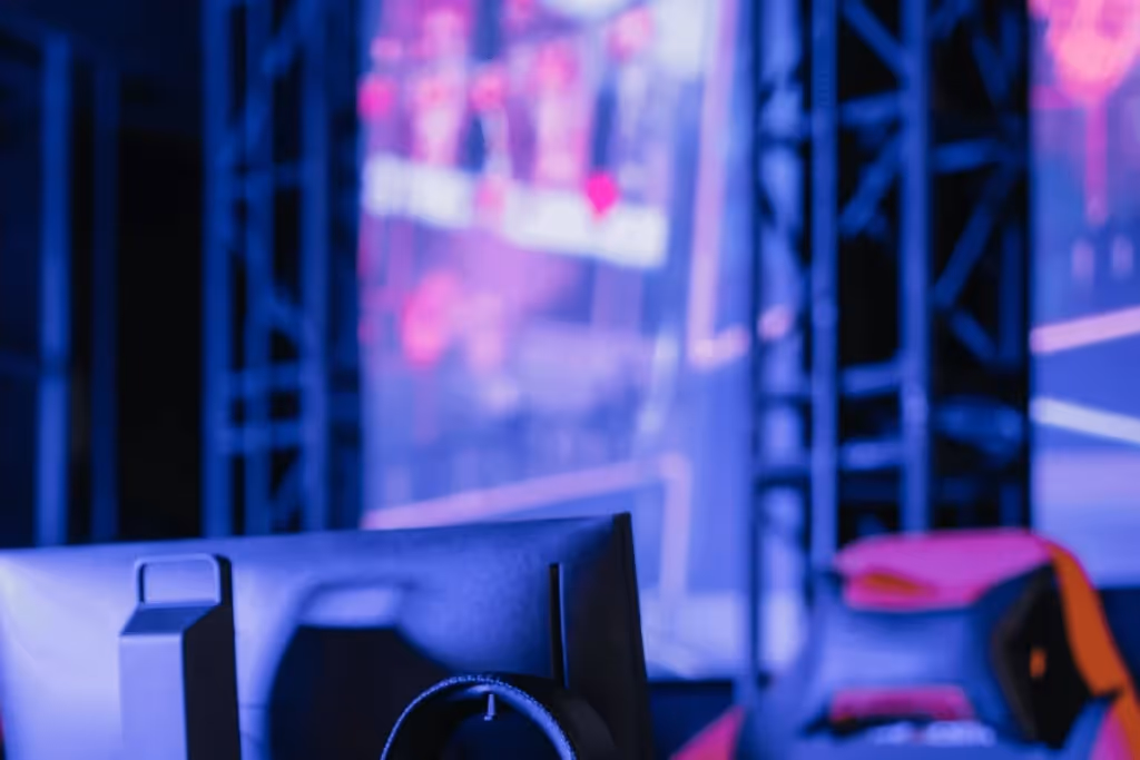 Close-up of a gaming monitor and chair with vibrant purple and blue lighting in the background