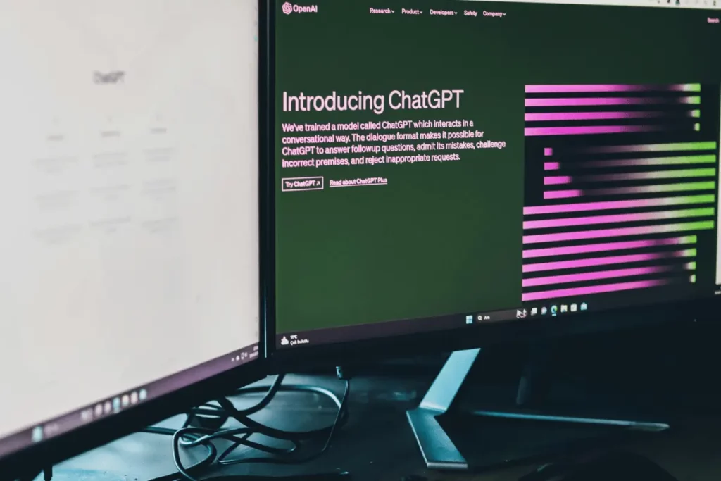 Dual monitors displaying ChatGPT interface and introductory page in a dark-themed workspace.