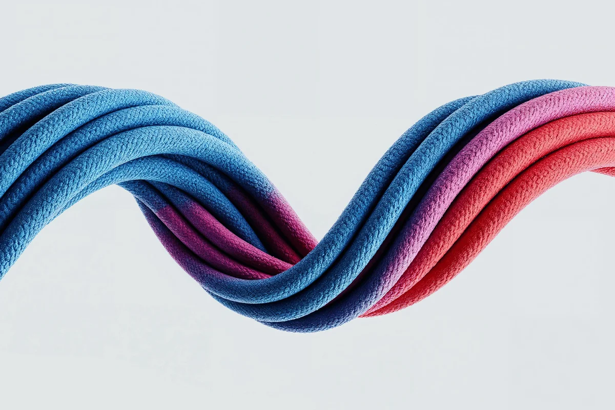 A twisted braid of blue, purple, and pink ropes against a light gray background, showcasing a blend of textures and colors, creating a sense of fluidity and motion.