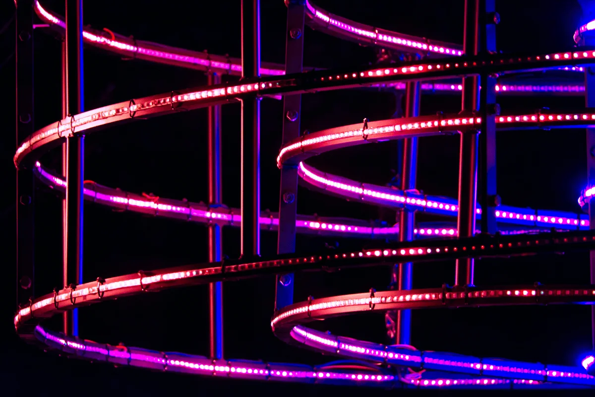 Close-up of illuminated spiral structure with colorful LED lights on dark backdrop.
