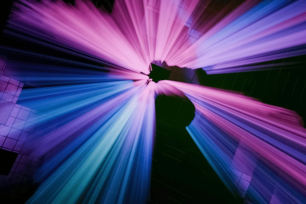 Abstract image of light beams in a spectrum of purple and blue, converging in the center.