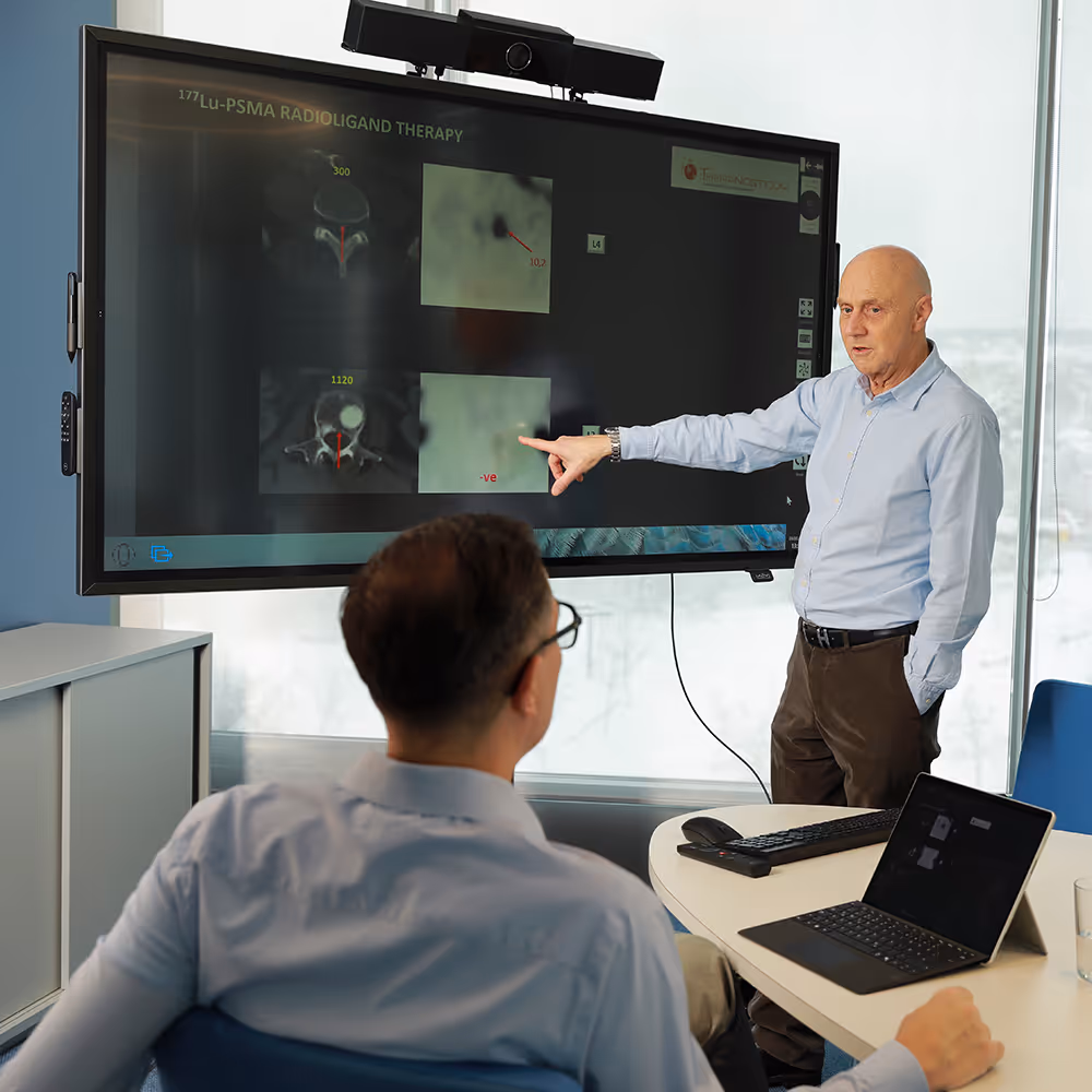 Dr. Werner Langsteger discusses medical imaging related to ¹⁷⁷Lu-PSMA radioligand therapy with Dr. Marcus Hacker on a large screen at Theranosticum Vienna.