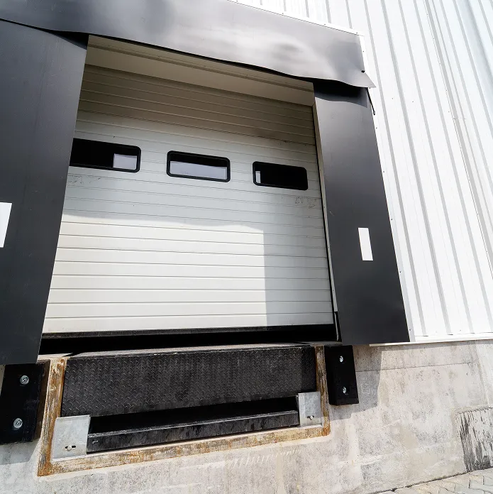 Closed industrial loading dock door with black rubber bumpers and concrete platform.