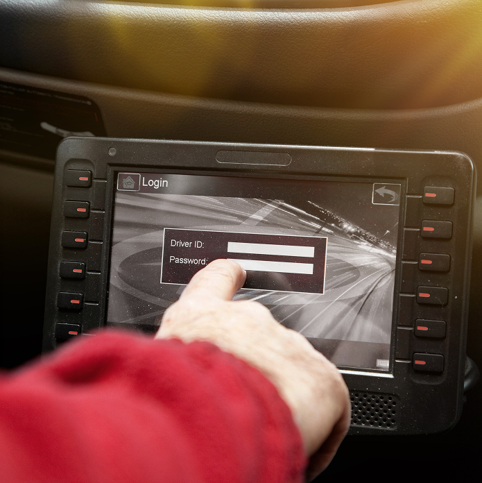 Hand in red sleeve pointing at a touchscreen display showing a login interface with fields for Driver ID and Password inside a vehicle.