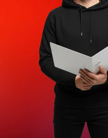 Person in black hoodie holding an open white binder against a red gradient background.