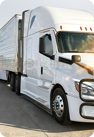 White semi-truck with a trailer parked on concrete under a clear sky.