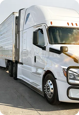 White semi-truck with a trailer parked on concrete under a clear sky.