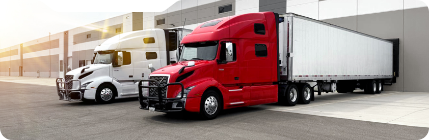 Red and white semi trucks parked next to a warehouse loading dock.