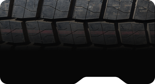 Close-up of black tire tread with rectangular patterns and visible dirt.