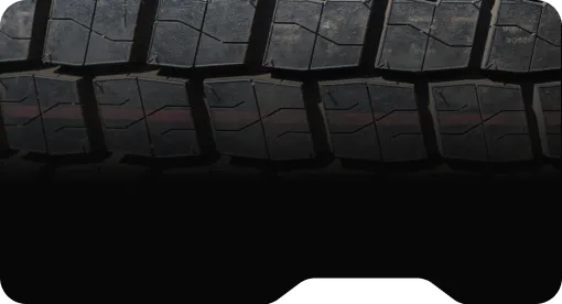 Close-up of black tire tread with rectangular patterns and visible dirt.