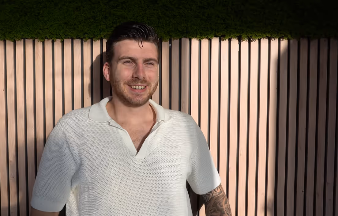 Lachende man met wit gebreid shirt in een kantoor