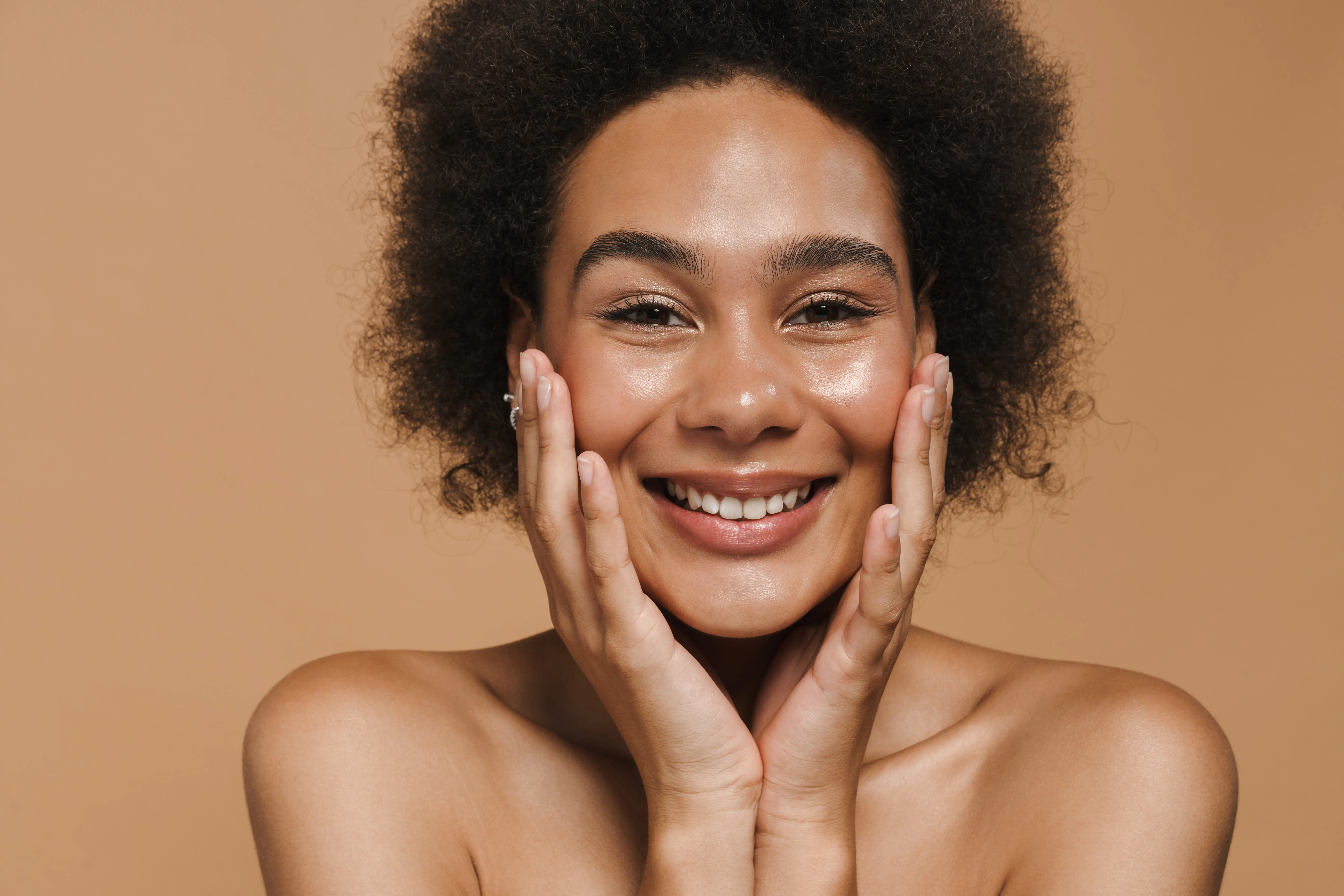 A woman smiling with her hands on her face.