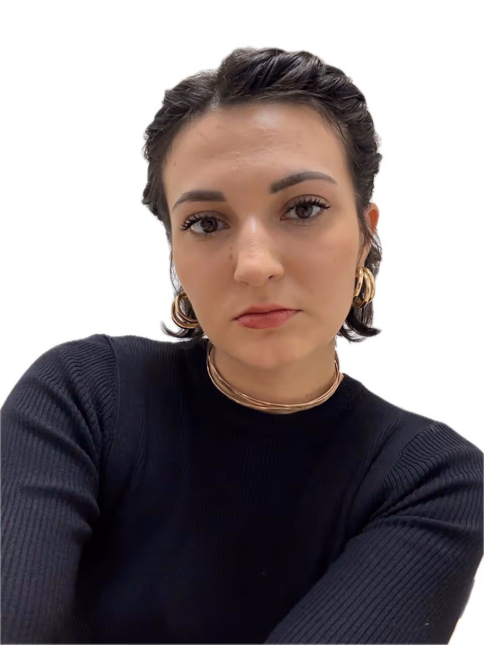 Kobieta z krótkimi ciemnymi włosami, nosząca czarny sweter oraz złote kolczyki i naszyjnik, patrzy prosto w kamerę.