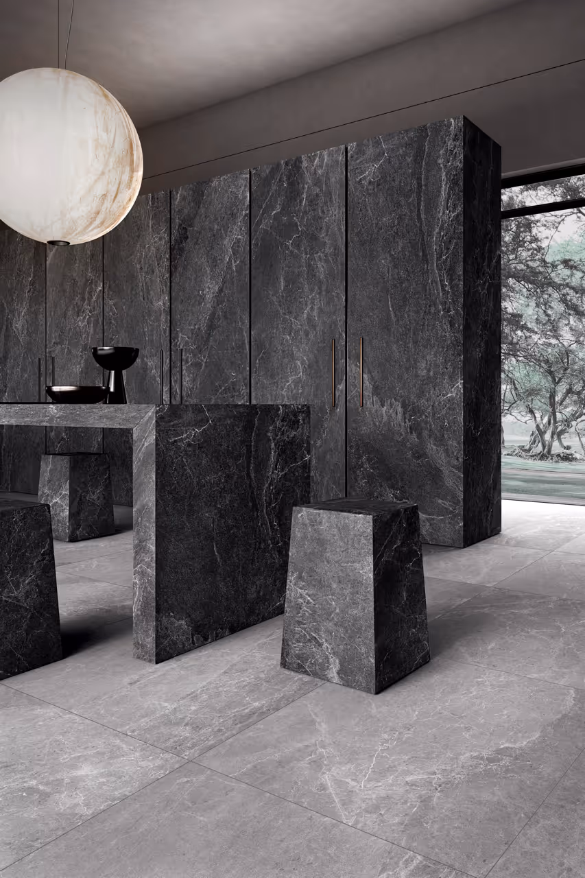 Nowoczesna kuchnia z czarnym marmurowym stołem, stołkami i szafkami oraz białą kulistą lampą wiszącą.