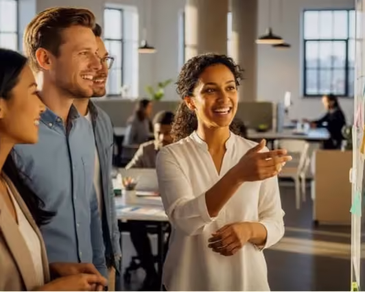 A group of four diverse colleagues smiling and discussing ideas in a modern office.