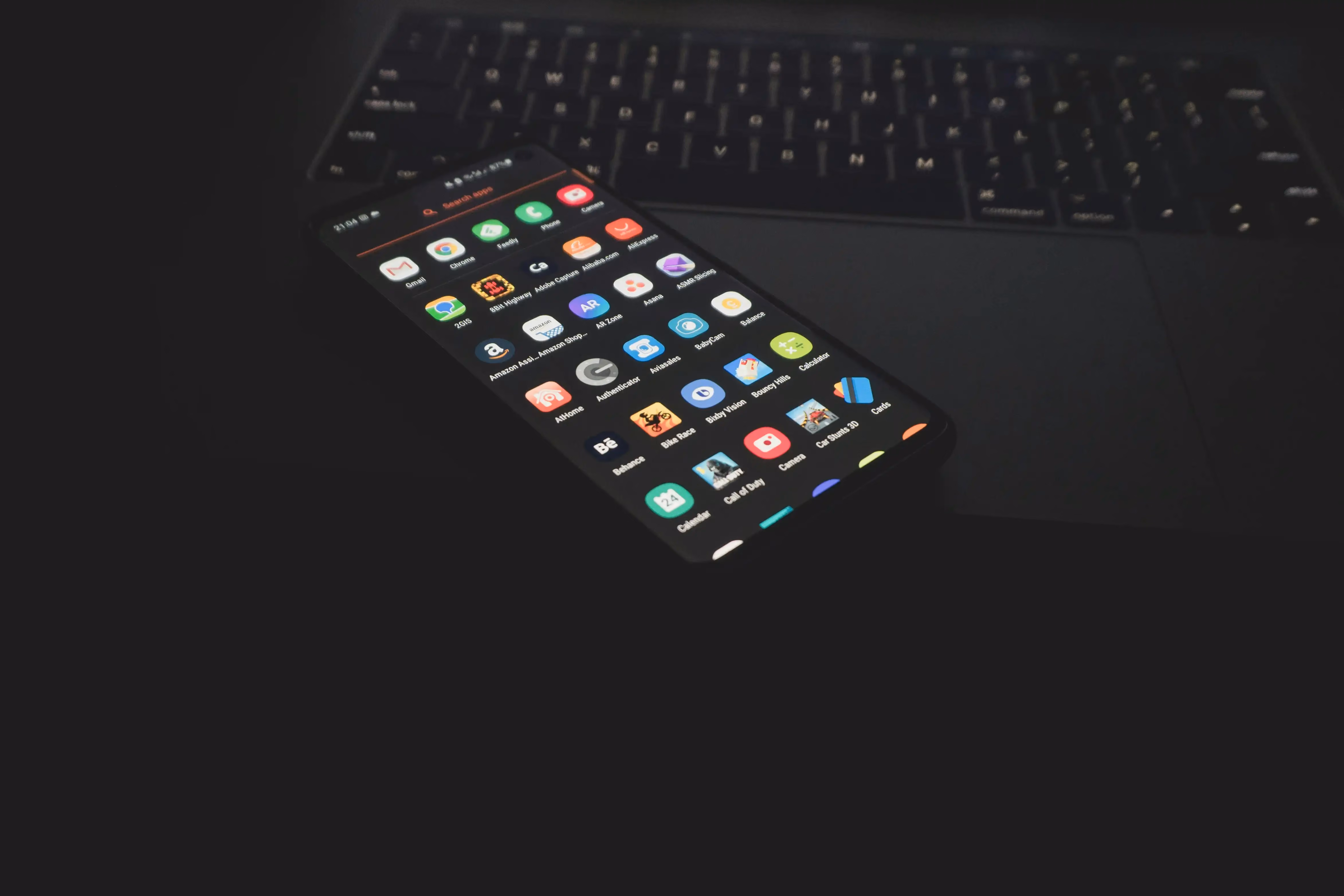 Smartphone displaying multiple colorful app icons lying on a dark laptop keyboard.