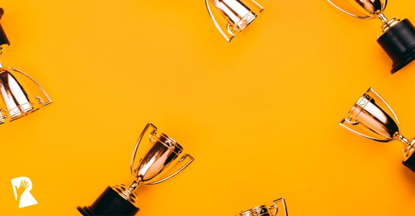 Gold trophies with black bases arranged around edges on an orange background.
