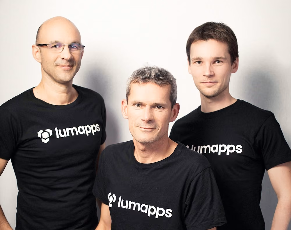 Three men wearing black Lumapps t-shirts posing against a plain white background.