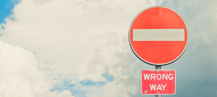 A "Do Not Enter" road sign with a red circle and white bar above a smaller "WRONG WAY" sign highlights the importance of clear messaging—much like using WhatsApp for business communication, set against a partly cloudy sky. Beekeeper