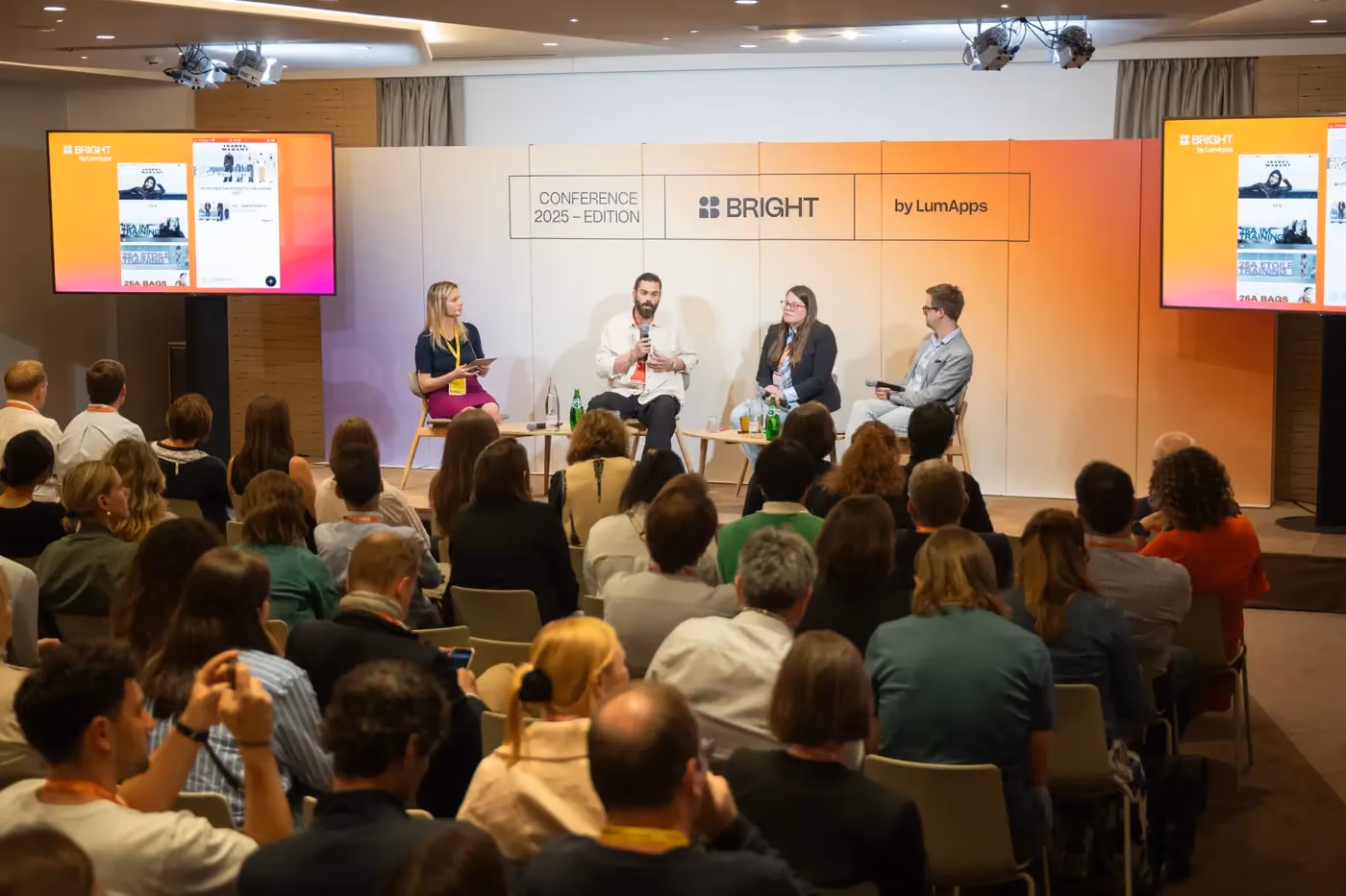 Panel of four discussing on stage at Bright by LumApps Conference 2025 with an attentive audience.