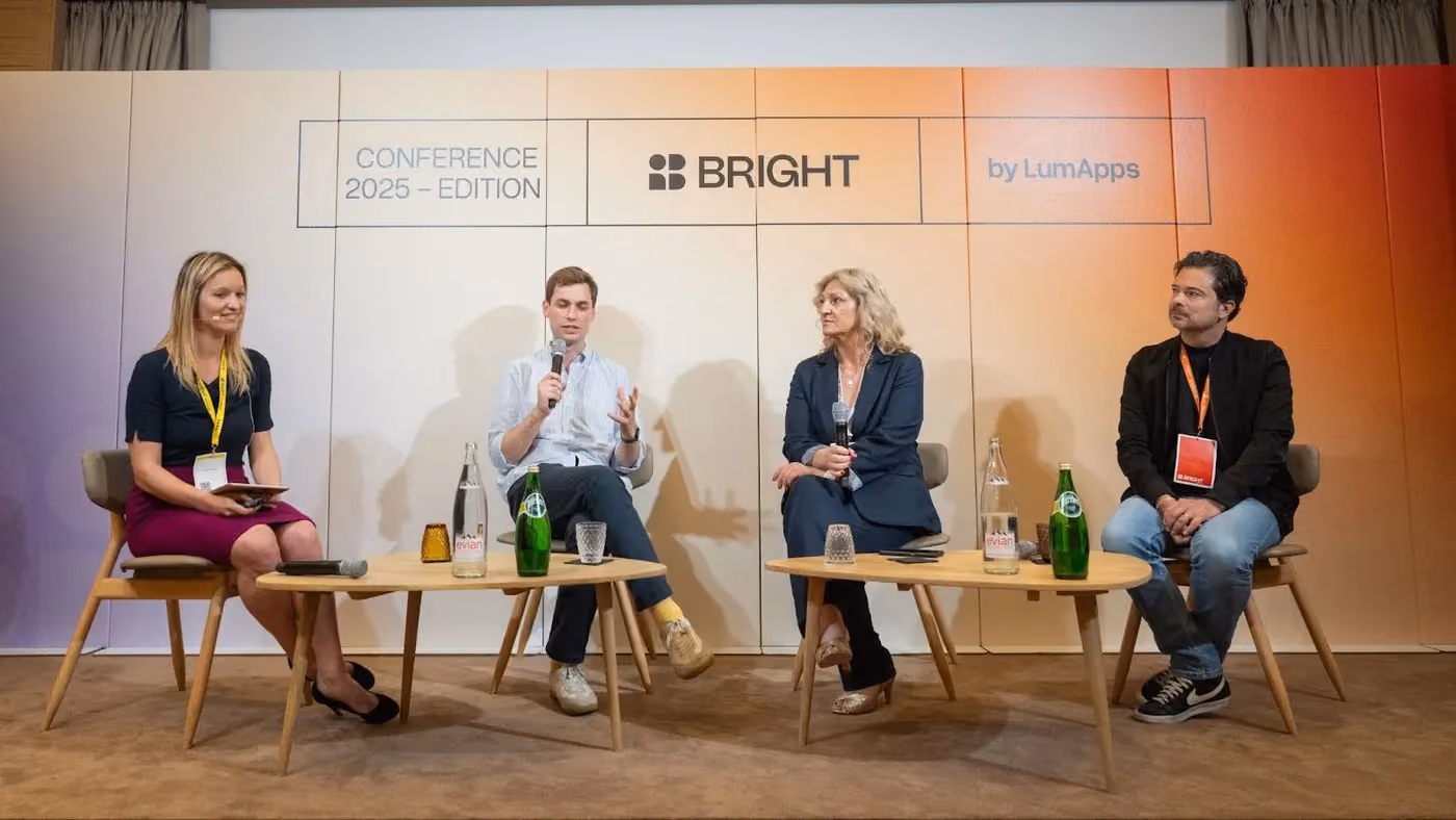 Four panelists seated on chairs with tables, speaking at BRIGHT Conference 2025 by LumApps.