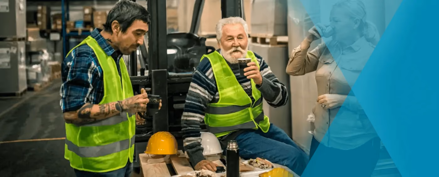 Three warehouse workers in safety vests taking a break, drinking coffee, and eating lunch.
