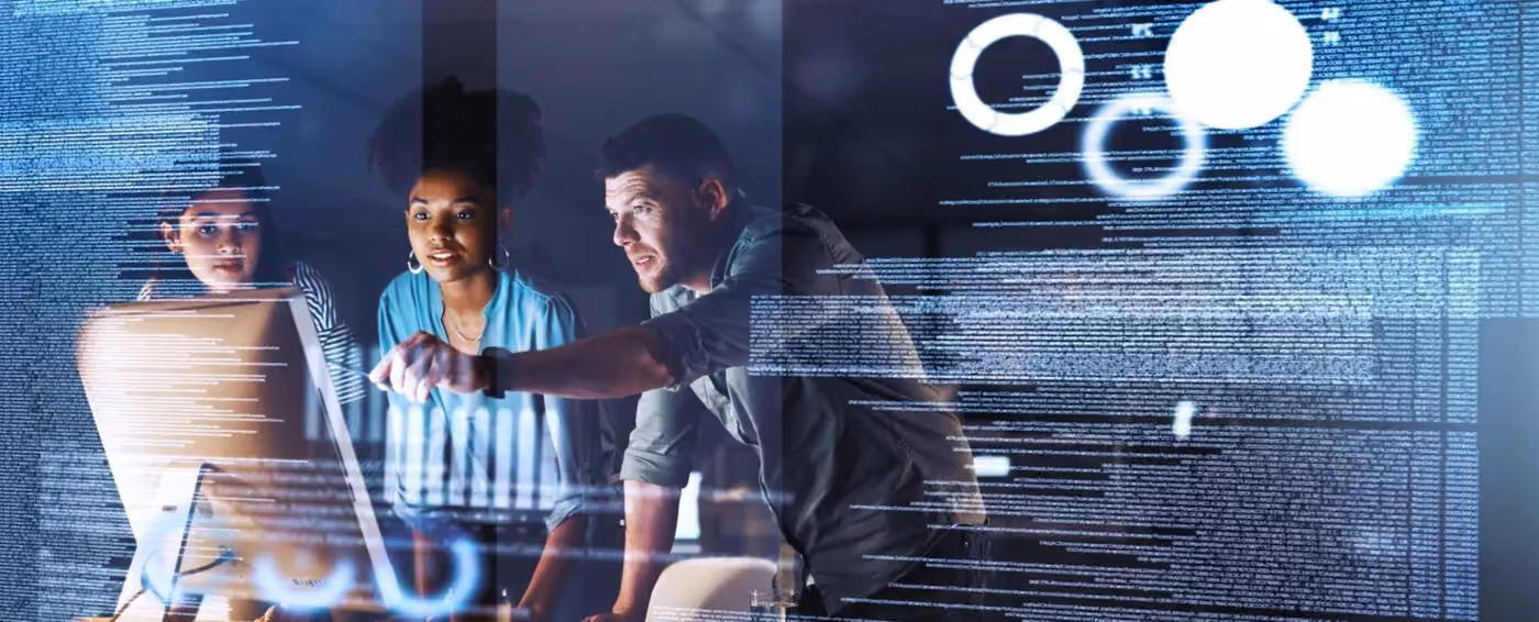 Three people looking at a computer screen with digital data and charts projected around them.