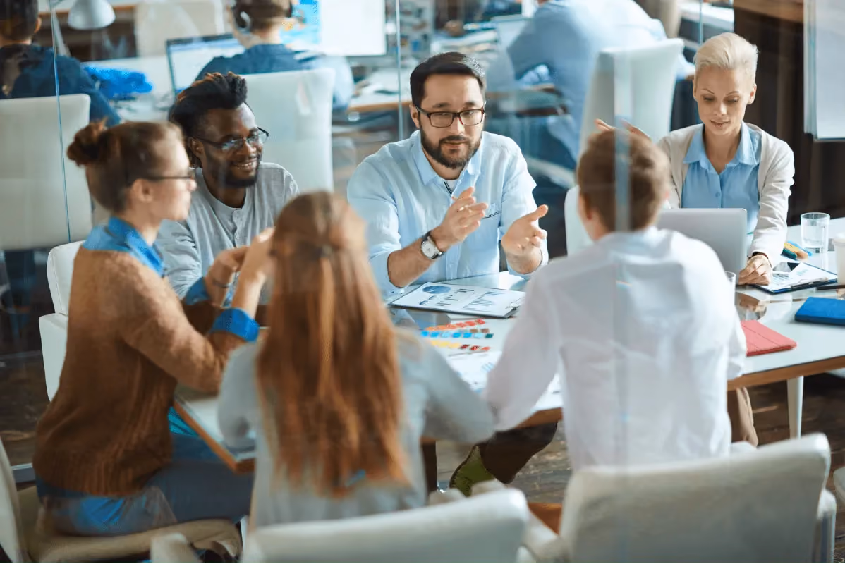 Diverse business team in a meeting around a table with charts and a laptop in an office.