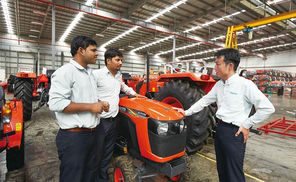 Kubota team members inspecting a tractor together on the factory floor