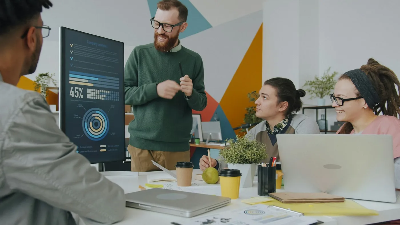 A team reviews a data dashboard on a large screen during an office meeting