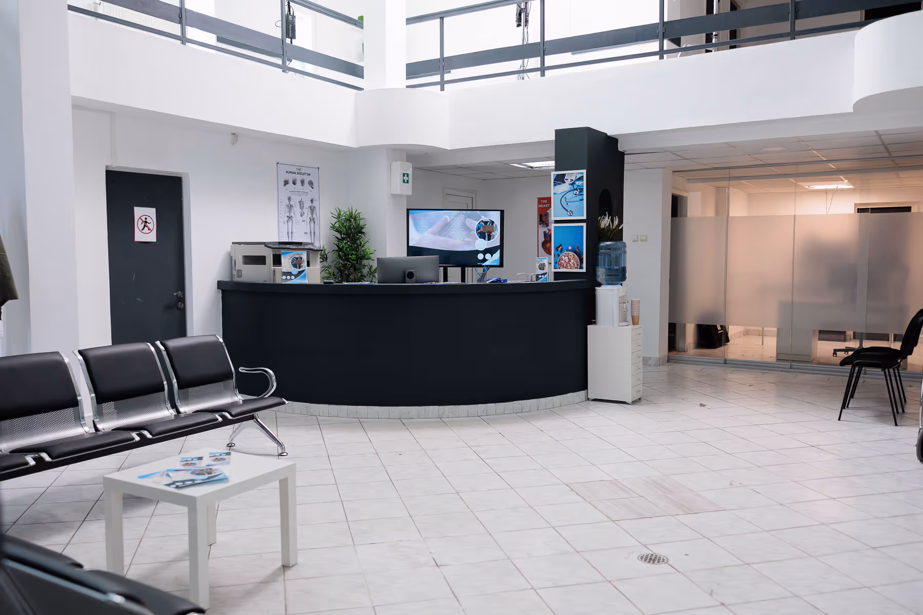 An empty, modern reception area with black chairs and a curved black desk in the center.
