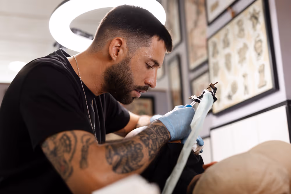 Tattoo artist carefully works on a design on a client's arm in a studio.