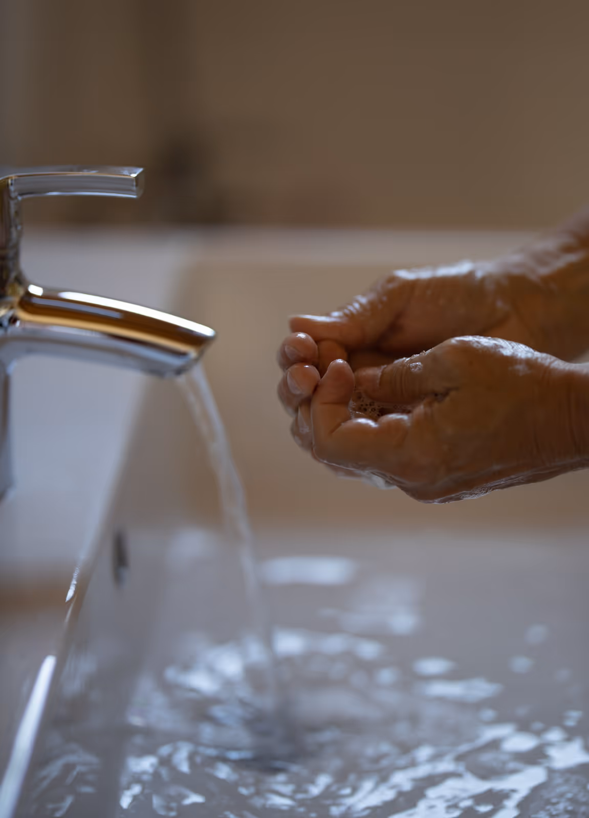 Person washing hands under running water from a sink tap.