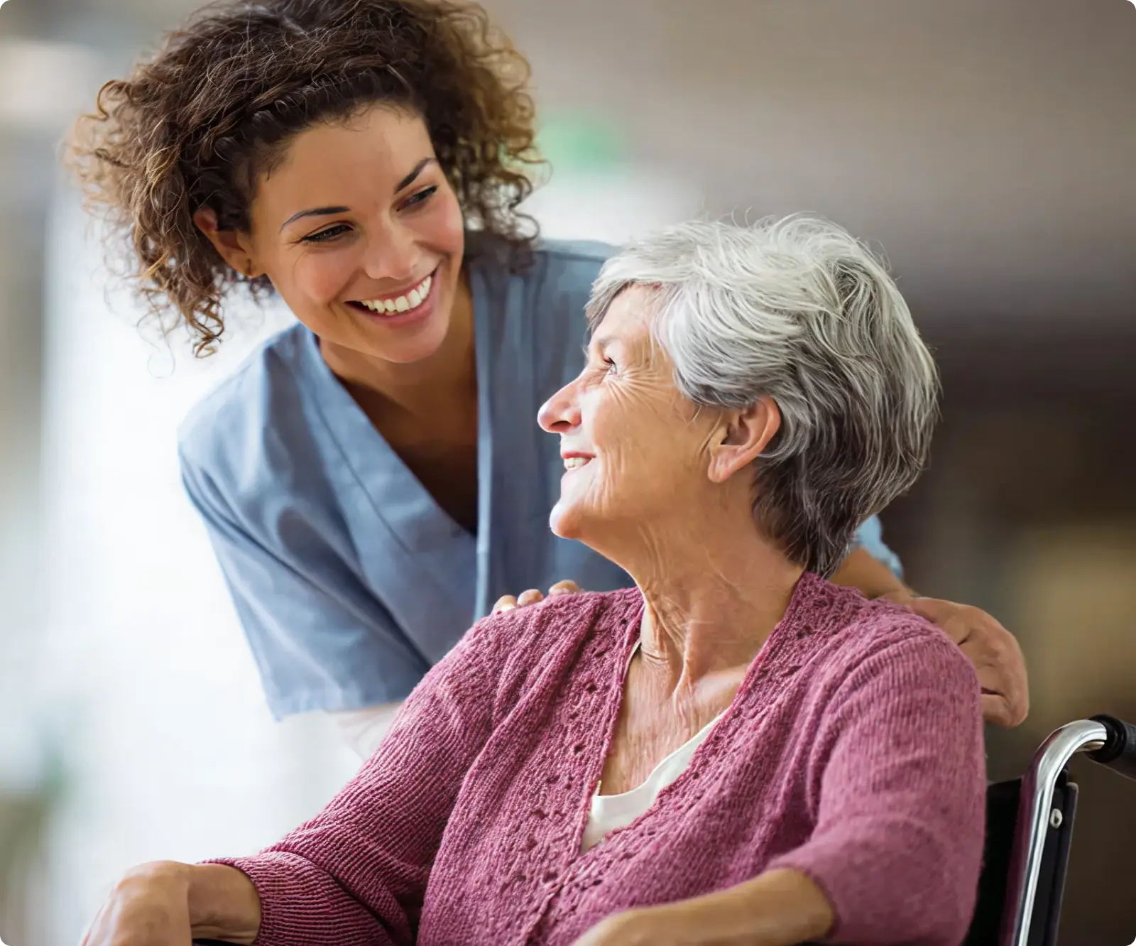 A smiling woman in a wheelchair with a nurse.