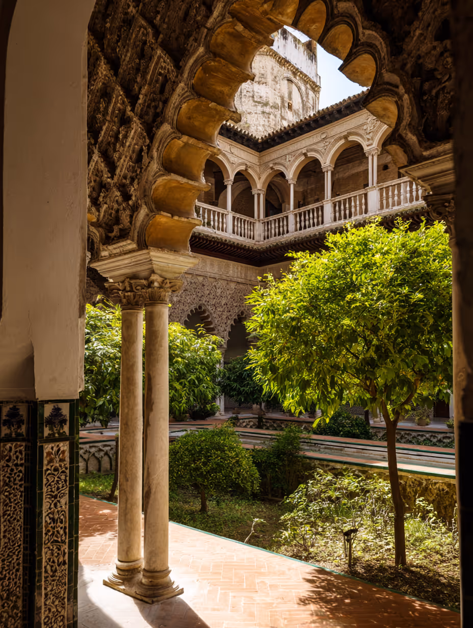 Binnenplaats van een Moorse paleis met stenen zuilen, boogvormige openingen, stenen balkon en weelderige groene bomen.