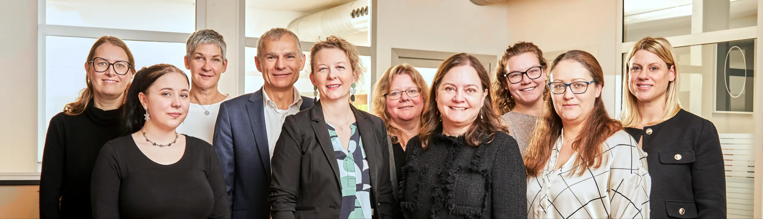 Gruppenfoto von Gründungsberatungsteam in einem hellen Büro, alle lächeln in die Kamera.