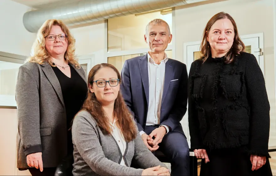 Porträt von zwei Buchhalterinnen und einem Steuerberater im Anzug, mit einer weiteren Steuerberaterin im Vordergrund, alle im auditax Büro.