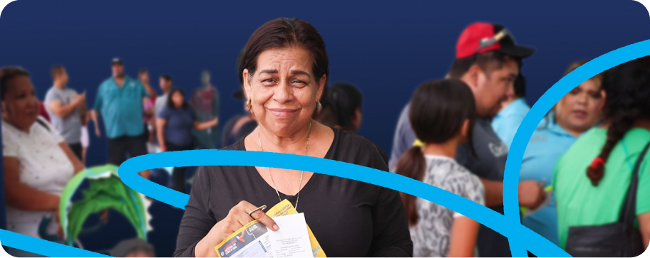 Persona sonriendo con materiales de Toma Segura en un evento comunitario