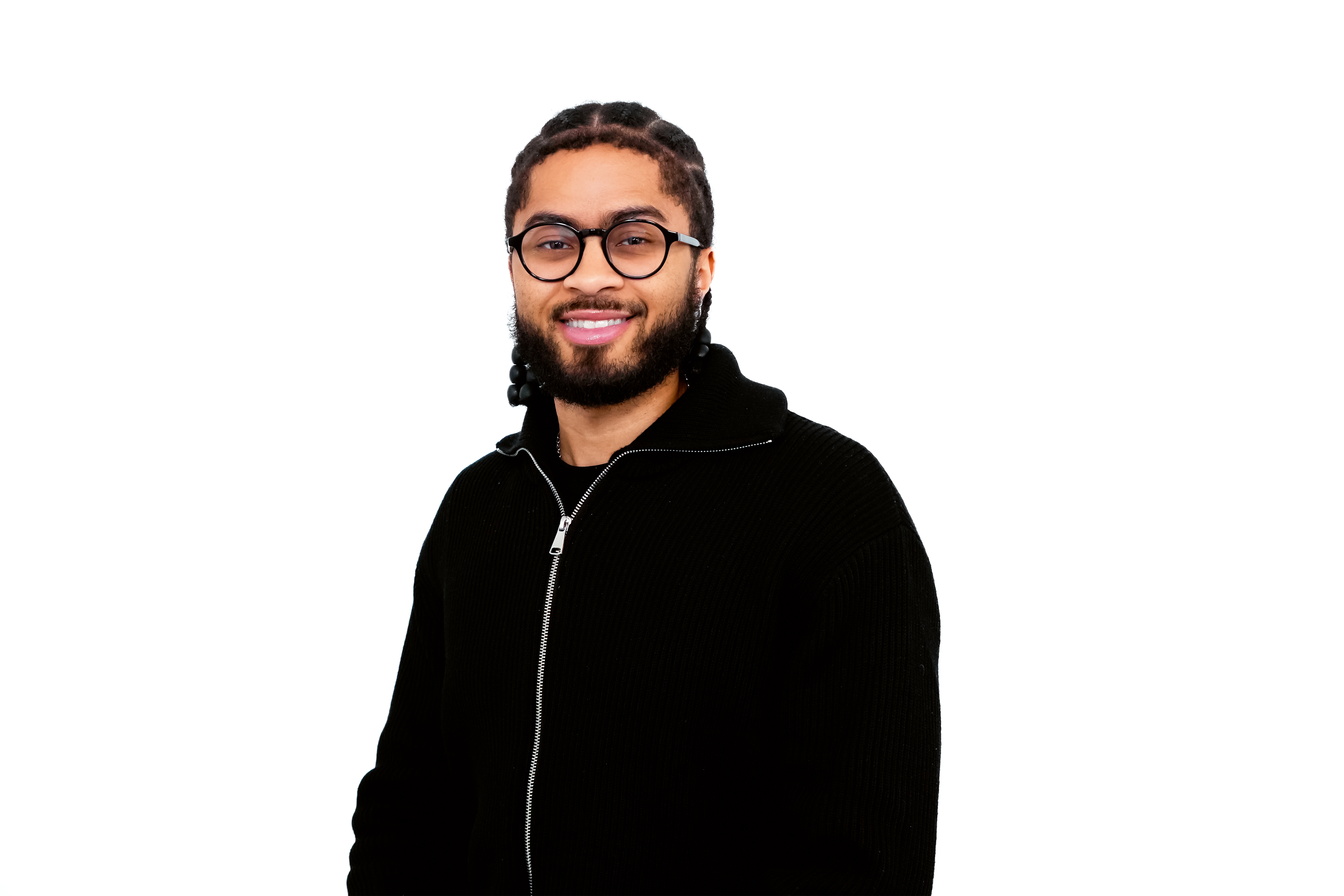 Smiling man with glasses, beard, and braided hair wearing a black zip-up sweater.