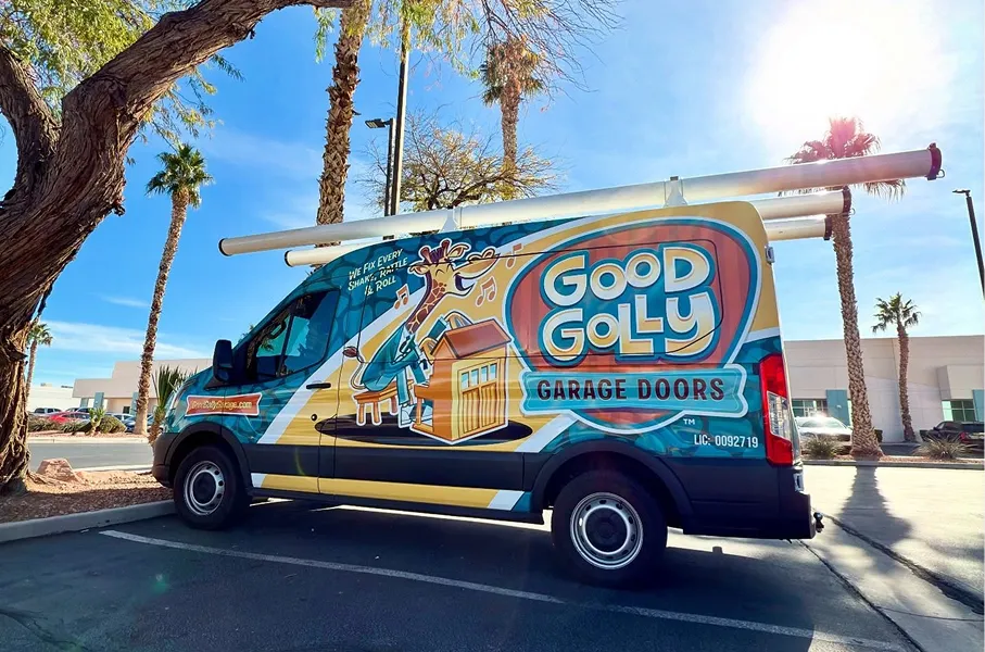 Colorful Good Golly Garage Doors service van parked outside with palm trees and clear blue sky in the background.