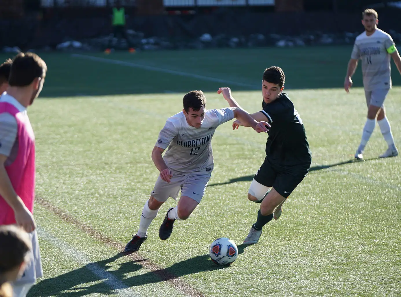 Een voetballer die met een actie de verdediger probeert te passeren.