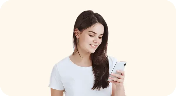 Young woman with long dark hair wearing a white t-shirt looking at her smartphone and smiling.