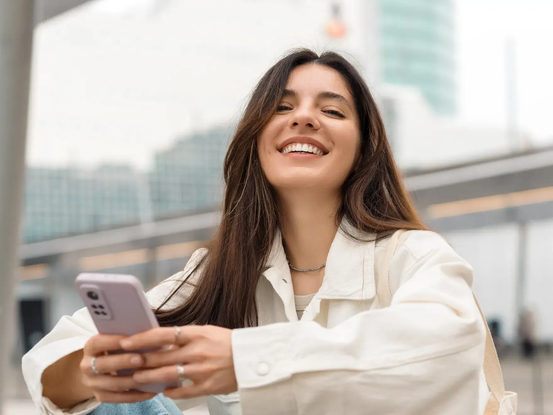 A woman smiles while holding a dental retainer in her hands.