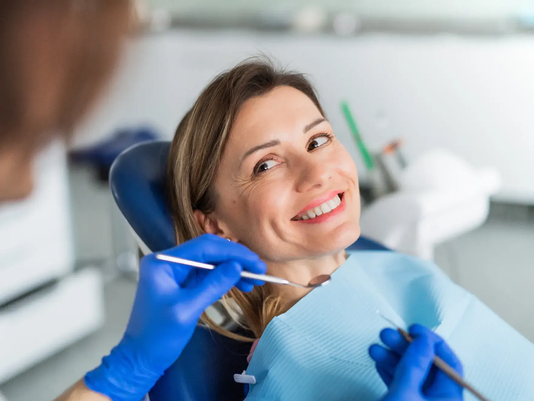 Person holding a dental aligner being handed to them by someone wearing blue gloves.
