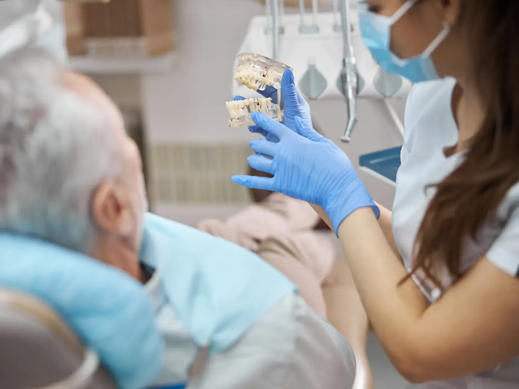 A patient wearing sunglasses smiles while two dental professionals prepare for a dental procedure.