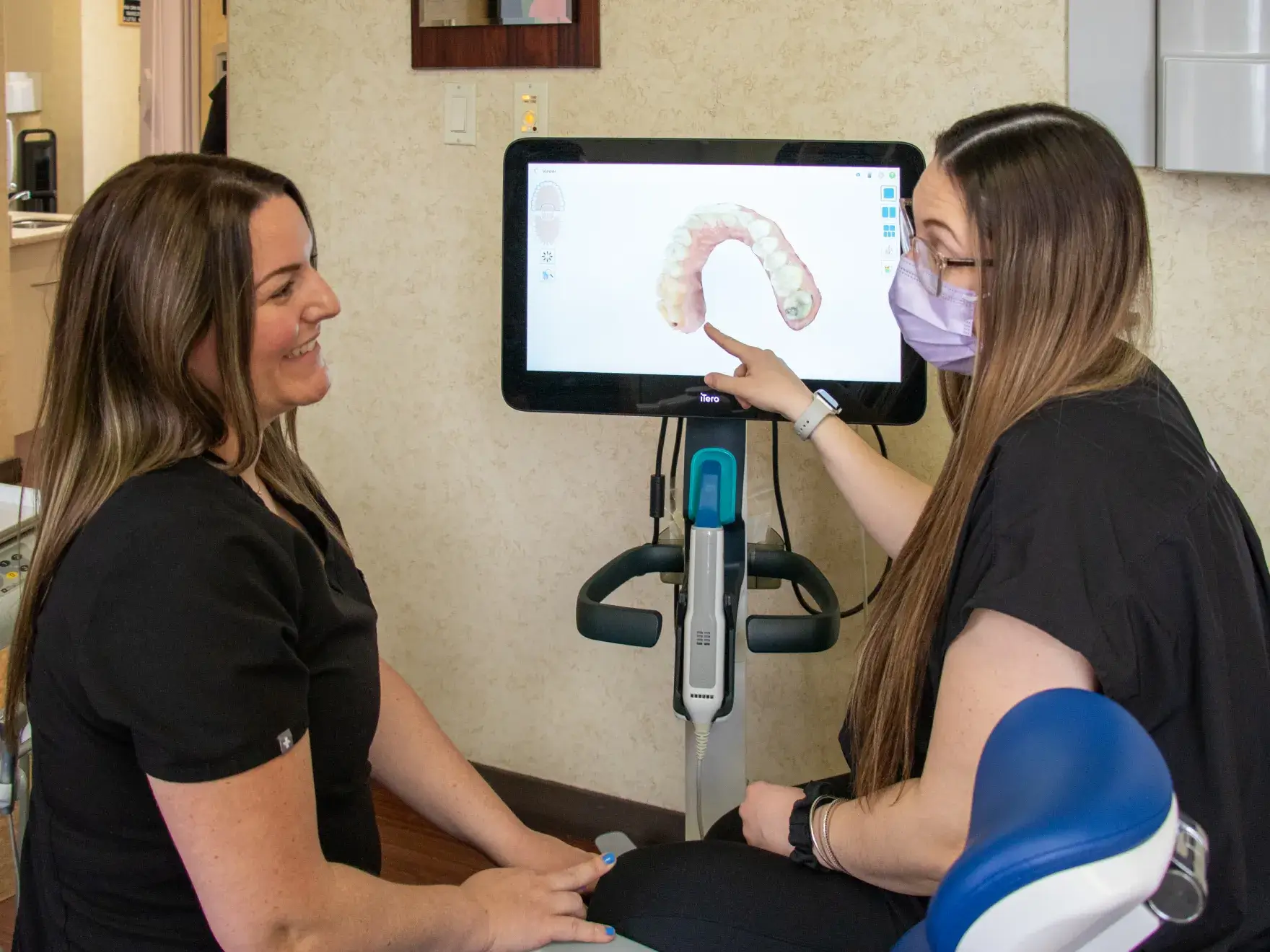 Two dental professionals discussing a digital image on a screen in a dental office.